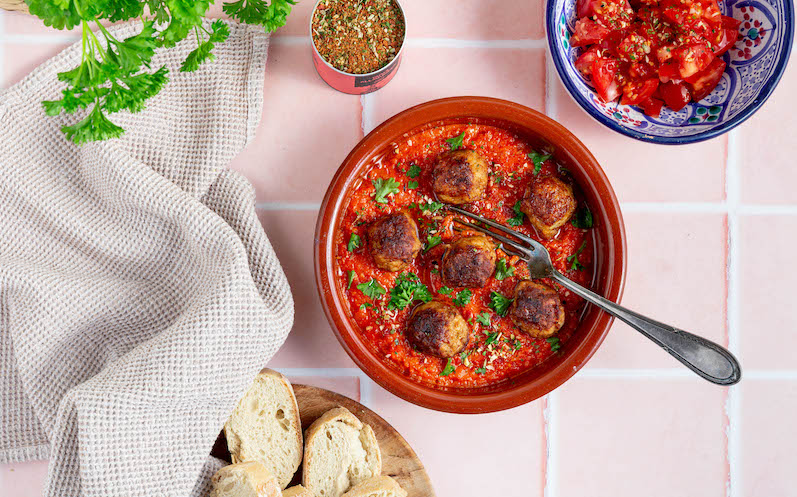 Spanische Frikadellen in fruchtiger Tomatensauce mit frischen Kräutern dekoriert