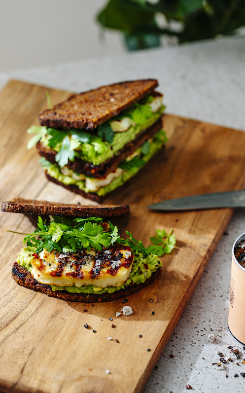 brot-mit-avocado-und-halloumi-auf-holzbrett