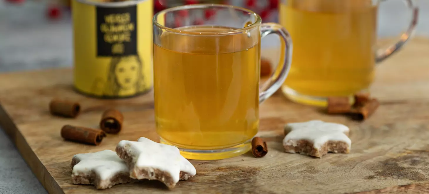 weisser-glühwein-in-tassen-und-zimtsterne-auf-einem-holzbrett-dekoriert