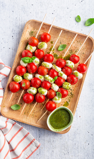 Tomate Mozzarella Spieße mit Basilikumpesto auf Holzbrett