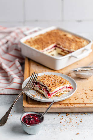 Spekulatius Tiramisu mit Waldbeeren in einer Auflaufform, ein Stück befindet sich bereits auf einem Teller 