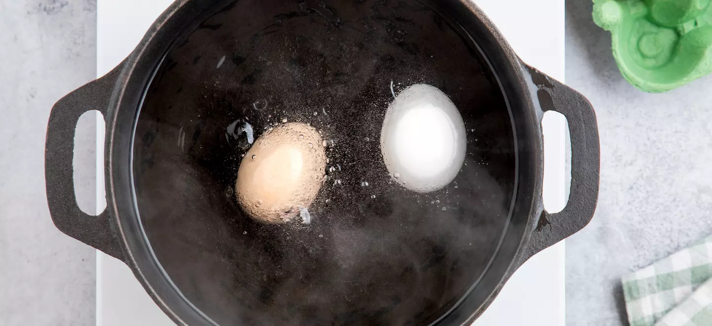 Ein weißes und ein braunes Ei kochen im Wasser 