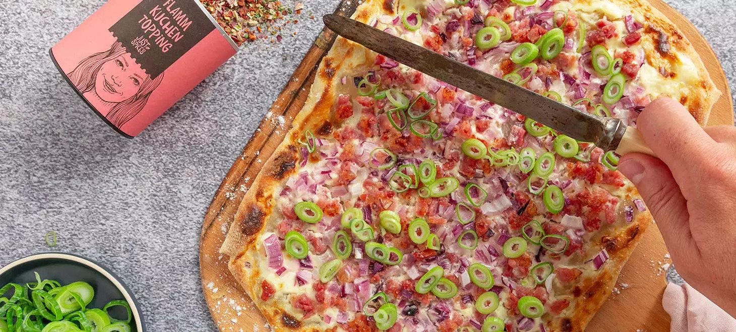 klassischer-flammkuchen-elsässer-art-mit-speck-zwiebeln-und-frühlingslauch-auf-einem-holzbrett